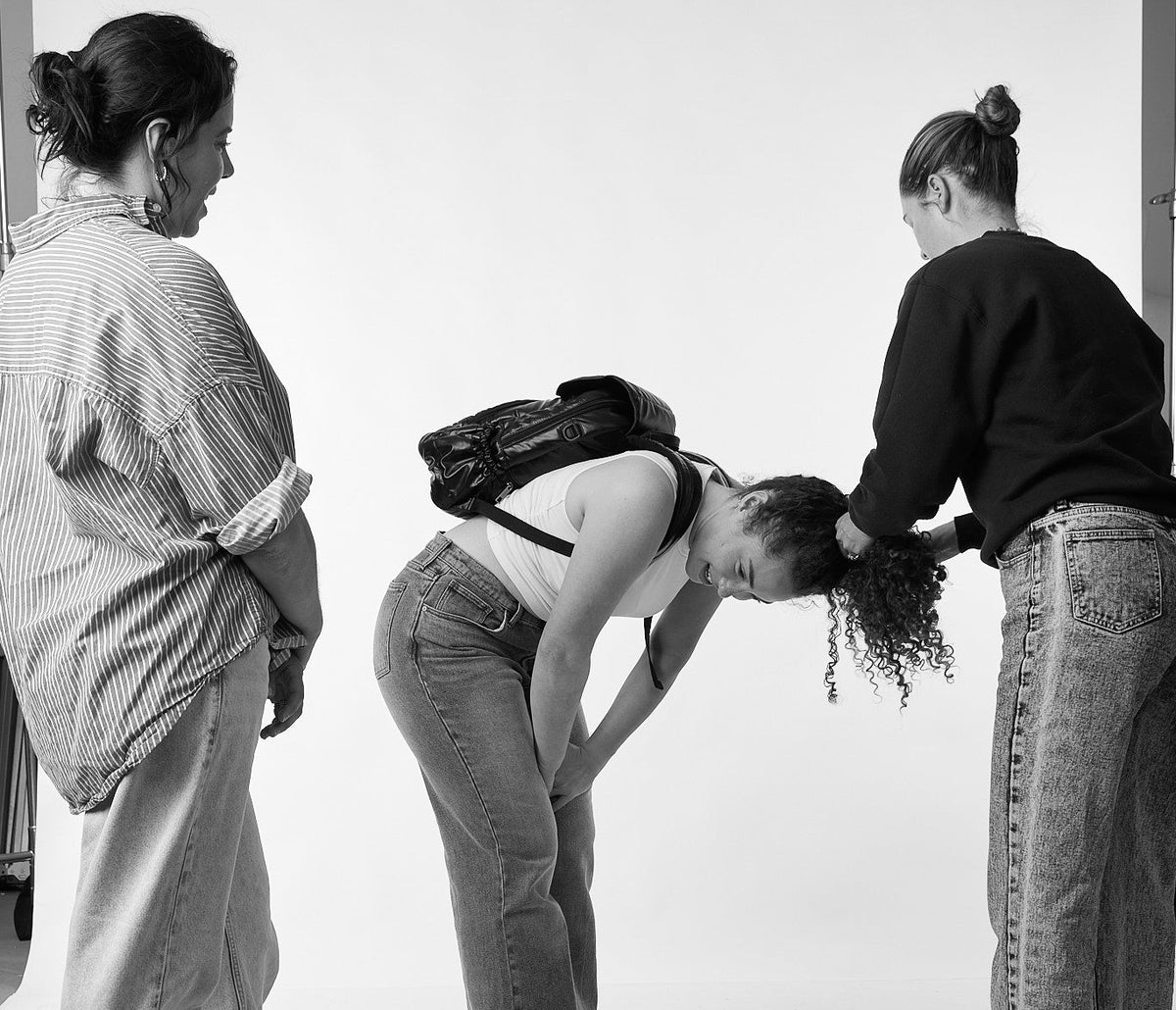 Three people interacting with a person lying on the floor against a white background
