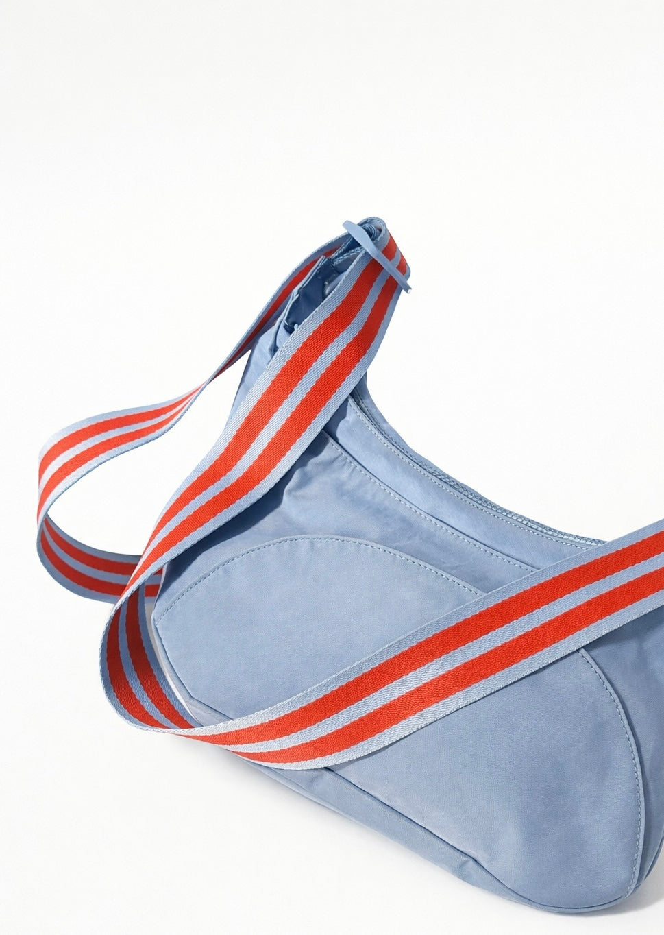 Light blue bag with a red and blue striped strap on a white background