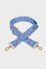 Blue bag strap with red cherry pattern on a light gray background