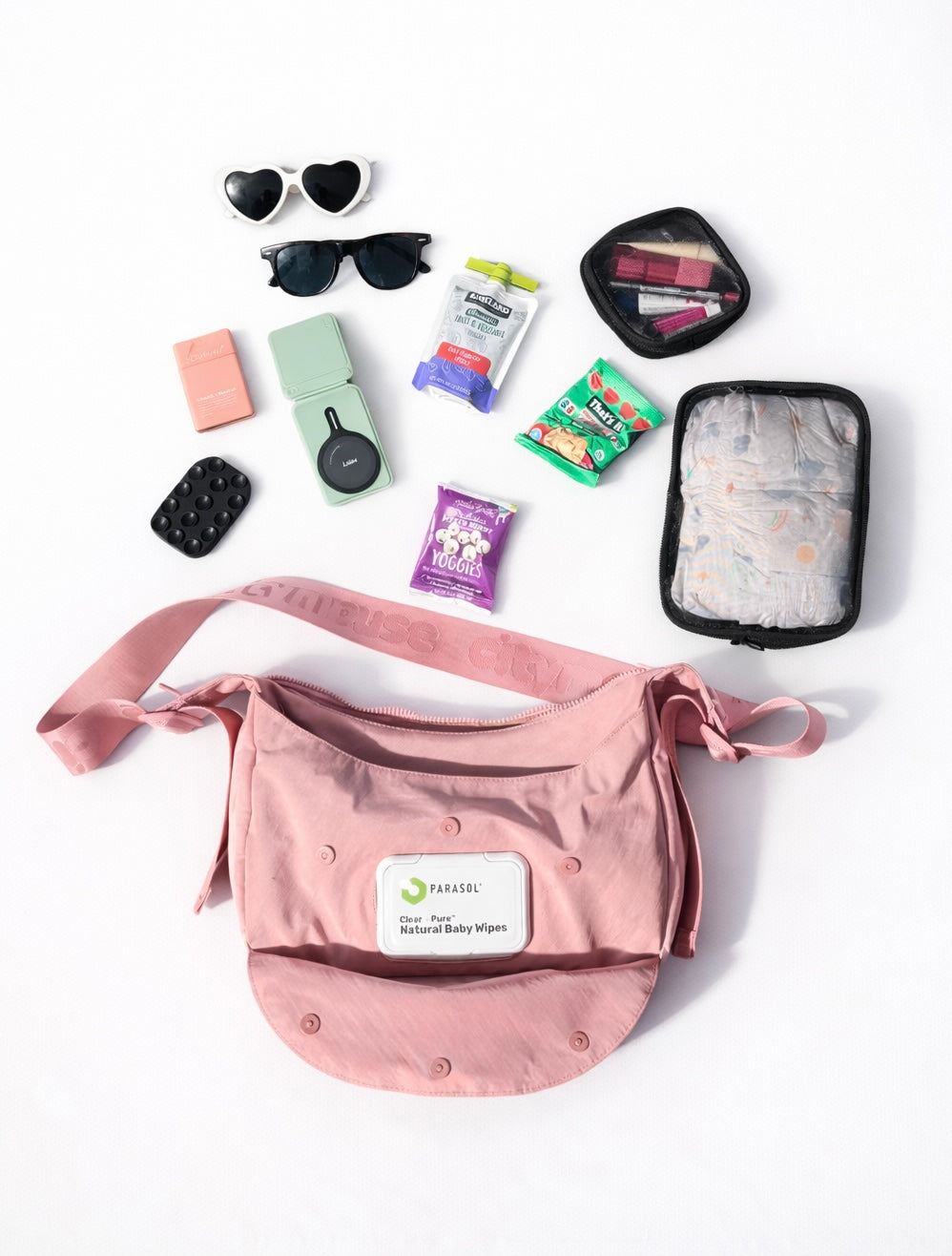Citymouse NY Park Bag in Baby/ Pink with travel essentials including sunglasses, lip balm, and toiletries on a white background